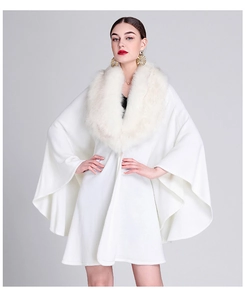 Detail view of white knit poncho featuring a premium faux fox fur collar and elegant drape