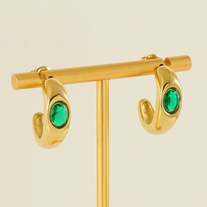 Detailed view of gold C-shaped earrings with inlaid green emerald cubic zirconia stones