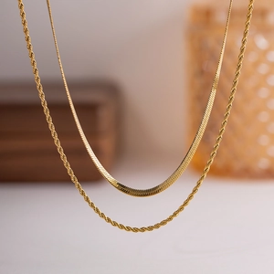 Detail of layered gold snake chain and rope chain necklace with elegant metallic shine