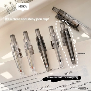 Detail shot of black neutral pens with modern high-gloss clips clipped onto a book page
