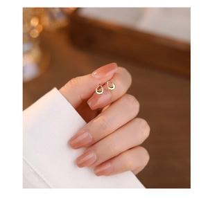 Close-up of hand holding golden teardrop hollow earrings in s999 sterling silver material