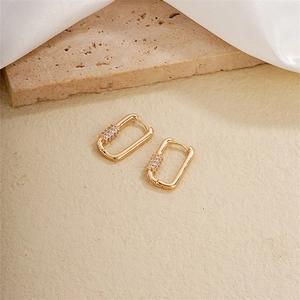 Detail of gold rectangular earrings featuring three rows of sparkling white zircons