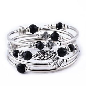Detail of silver layered bracelet with black lava beads and floral metal charms on white