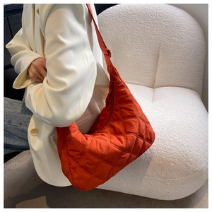 Detail of orange quilted nylon dumpling bag featuring elegant diamond lattice stitching