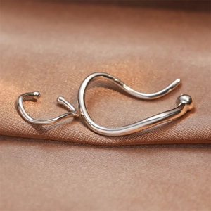 Minimalist silver wave geometric ear cuffs set on brown silk backdrop macro view