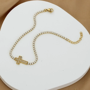 Elegant gold-plated cross tennis bracelet with cubic zirconia on geometric display