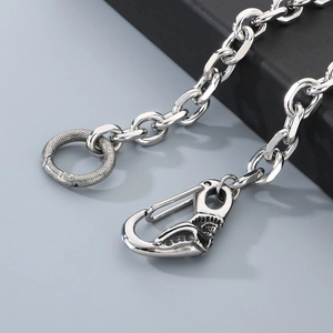 Detail of silver titanium trouser chain featuring skull clasp and snake pattern ring