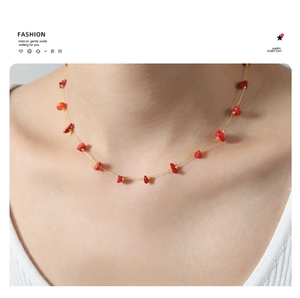 Close-up of minimalist gold chain necklace featuring vibrant red natural stone beads on a model