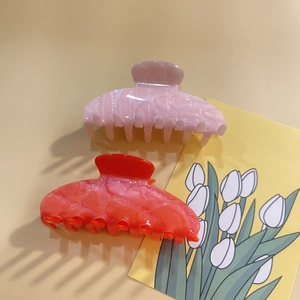Detail of pink and orange large glitter acrylic shark hair claws with a tulip card