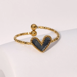 Dettaglio macro anello cuore dorato con trama martellata e smalto nero centrale