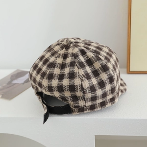 Close-up of retro plaid fabric texture and adjustable black strap on kid's beret hat