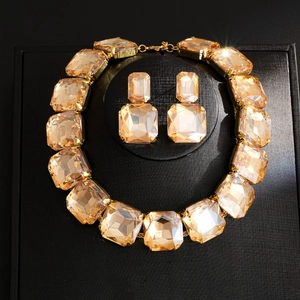 Exquisite gold necklace and earring set with amber drop zircons on a black stand