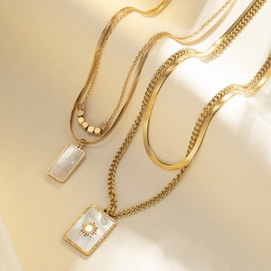 Dual-layer gold titanium necklaces with shell pendants on elegant beige silk fabric