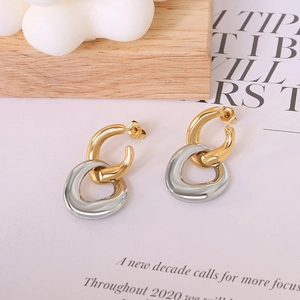 Minimalist interlocking C-shape gold and silver hoop earrings on a magazine background