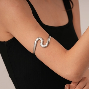 Polished silver wave arm cuff bracelet shown on model upper arm with minimalist design