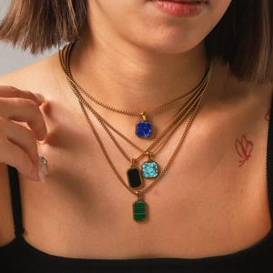 Detail of layered gold stainless steel necklaces with colorful natural stone pendants