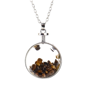 Detailed view of a round glass pendant filled with tiger eye stones on a silver chain