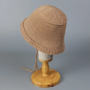 Detailed close-up of camel knit bucket hat texture and adjustable chin strap design