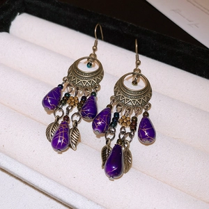 Detail of vintage bronze bamboo earrings with purple resin beads and tassels