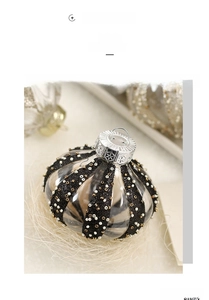 Detailed close-up of a clear painted Christmas ball with black glitter and gold beadwork