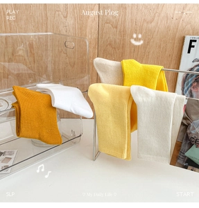 Close-up of ribbed cotton socks in mustard yellow and white on a lifestyle display
