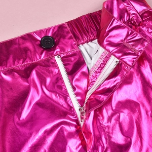 Detail of rose red shiny metallic pants featuring black button and silver zipper closure