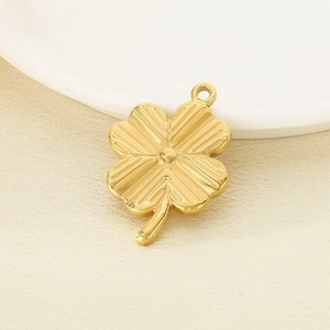 Detailed macro shot of a golden four-leaf clover pendant accessory on a white plate