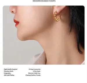 Détail de la boucle d'oreille perlée en C en acier titane plaqué or 18 carats sur modèle