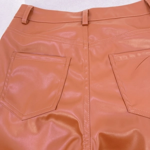 Detail der orangefarbenen PU-Lederhose mit hoher Taille, Gesäßtaschen und Nahtqualität