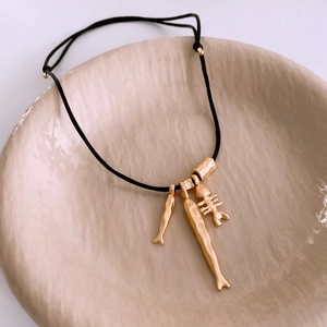 Detailed shot of fish bone and fish charms on adjustable black cord necklace