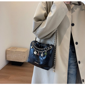 Close-up of quilted black bucket bag with gold chains and colorful heart charms