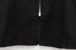 Dettaglio macro della cerniera in metallo argentato su tessuto denim nero