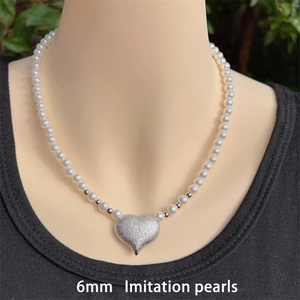 Detail of 6mm imitation pearls necklace with a matte heart pendant on mannequin