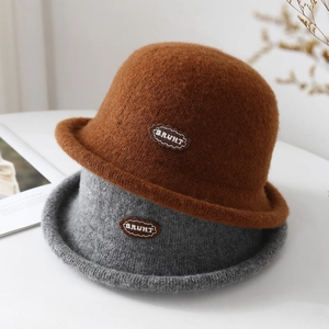 Detail of winter knitted bucket hats in brown and grey with vintage leather brand patch