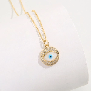 Golden Evil Eye pendant necklace with blue iris and sparkling zircon stones on white base