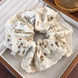 Close-up of beige floral scrunchie with lace trim in a wooden jewelry box display