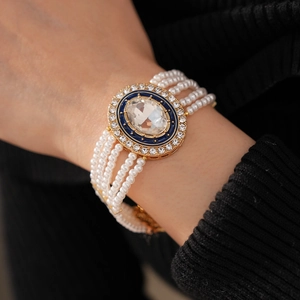 Detail of multilayer pearl bracelet with a large oval gemstone and blue enamel frame