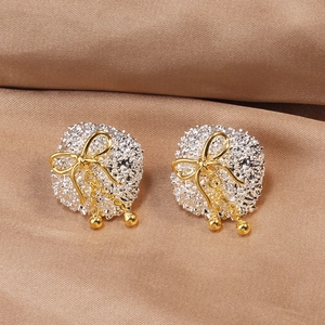Detail shot of silver textured base earrings with golden bows and small bead pendants