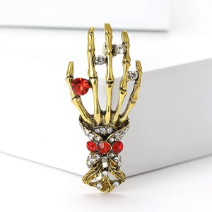 Retro punk style golden skeleton hand brooch with red rhinestones on white display stand
