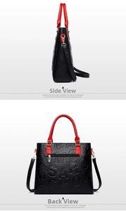 Detail view of black embossed leather handbag with red handles and gold hardware accents