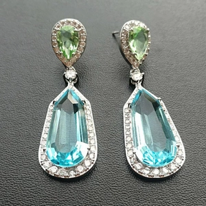 Detailed view of silver drop earrings featuring pear-cut green and blue zircon stones
