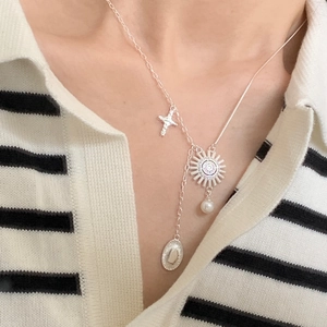 Detail of 925 silver sun goddess necklace with cross and pearl pendant on a model