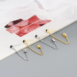 Macro view of gold and silver chain earrings with black round zircon insets