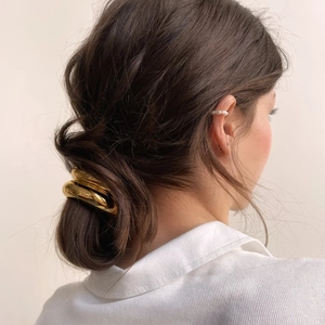 Close-up of a 18k gold-plated U-shaped hair tie on a minimalist low bun hairstyle