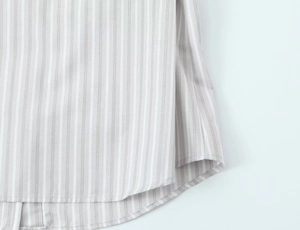 Détail de l'ourlet de la chemise à rayures montrant les coutures et le tissu en coton