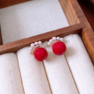 Detail of vintage earring with a large red bead, white pearls and gold metal base