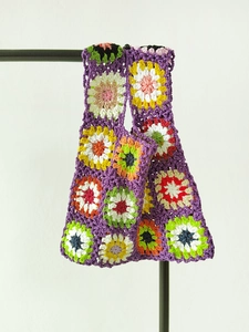 Detailed close-up of handmade granny square crochet patterns on a purple tote bag