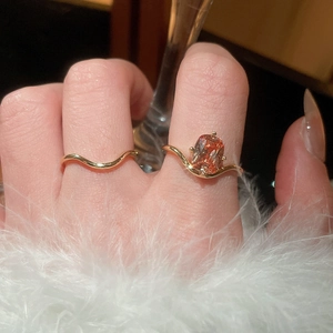 Detailed view of an 18k gold plated wavy ring set with an orange zircon gemstone