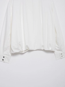 Detail view of white linen bomber jacket showing elastic hem and metal cuff buttons