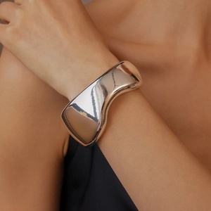 Close-up of a silver polished wide cuff bracelet with a flowing asymmetrical design